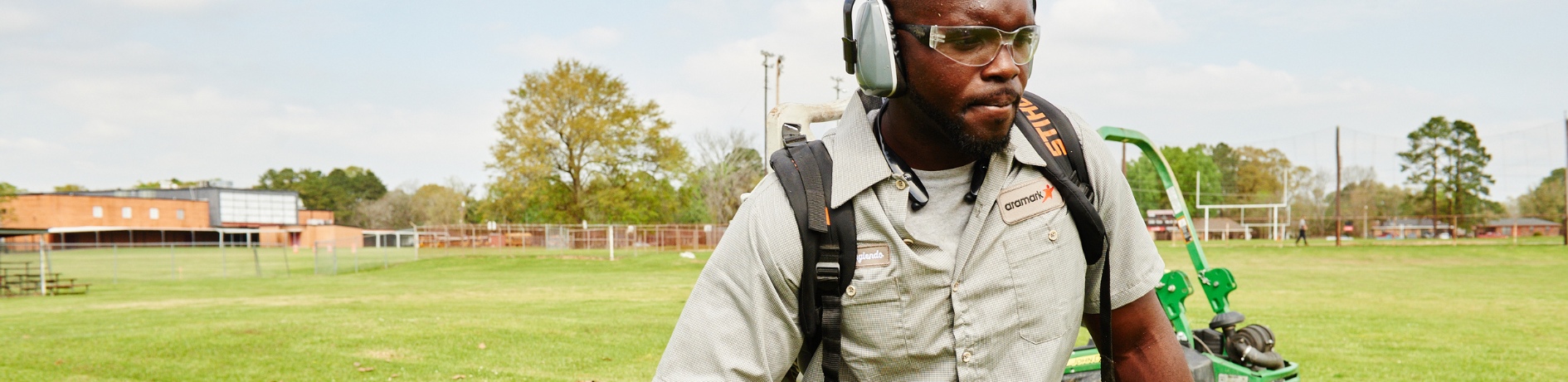 Aramark worker using a leafblower on a sports field.